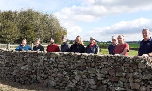 Group of people behind a dry stone wall