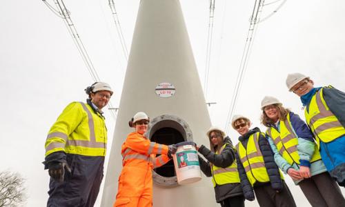 Students wearing hard hats and high-vis vests placing time capsule inside t-pylon