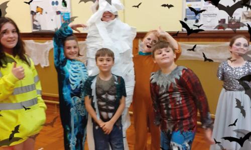 Children dressed in Halloween outfits with superimposed bats in the foreground