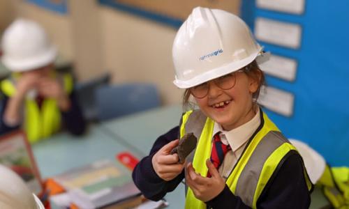 Child wearing National Grid hardhat and hi-vis vest in classroom