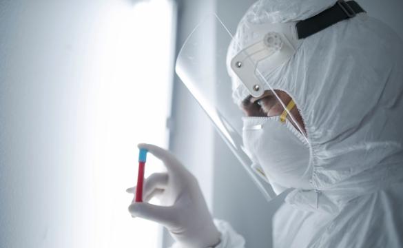 Person wearing full PPE holding blood vial used for National Grid 'Backing the quest for a COVID-19 vaccine' story
