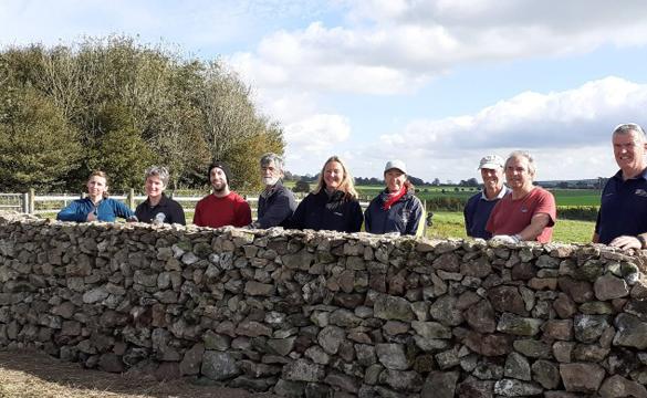 Group of people behind a dry stone wall