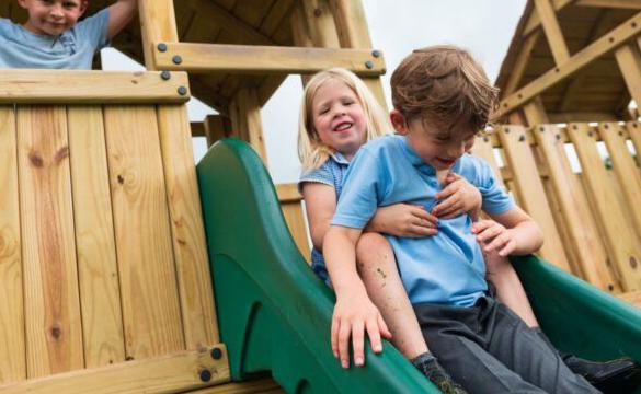 Young girl and boy sitting at the top of a slide