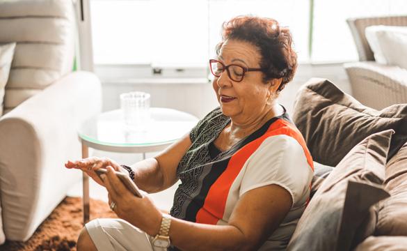 Lady on sofa looking at a mobile phone - National Grid's Grid for Good conference calls for elderly in Syracuse
