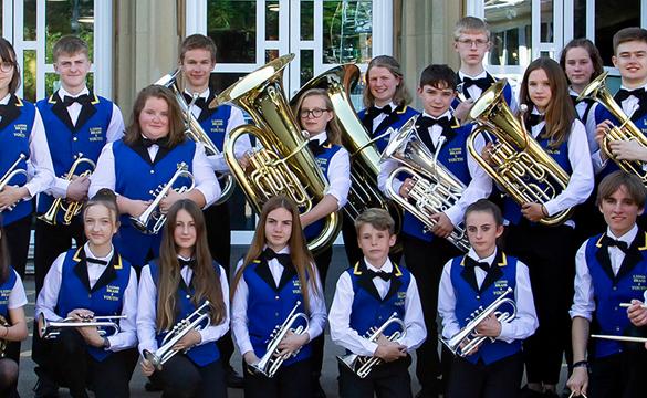 Youth brass band wearing uniform and holding their instruments