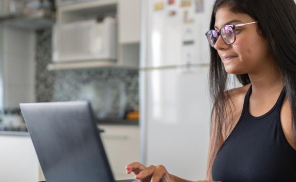 Young woman at kitchen table working on laptop for National Grid virtual interview skills story